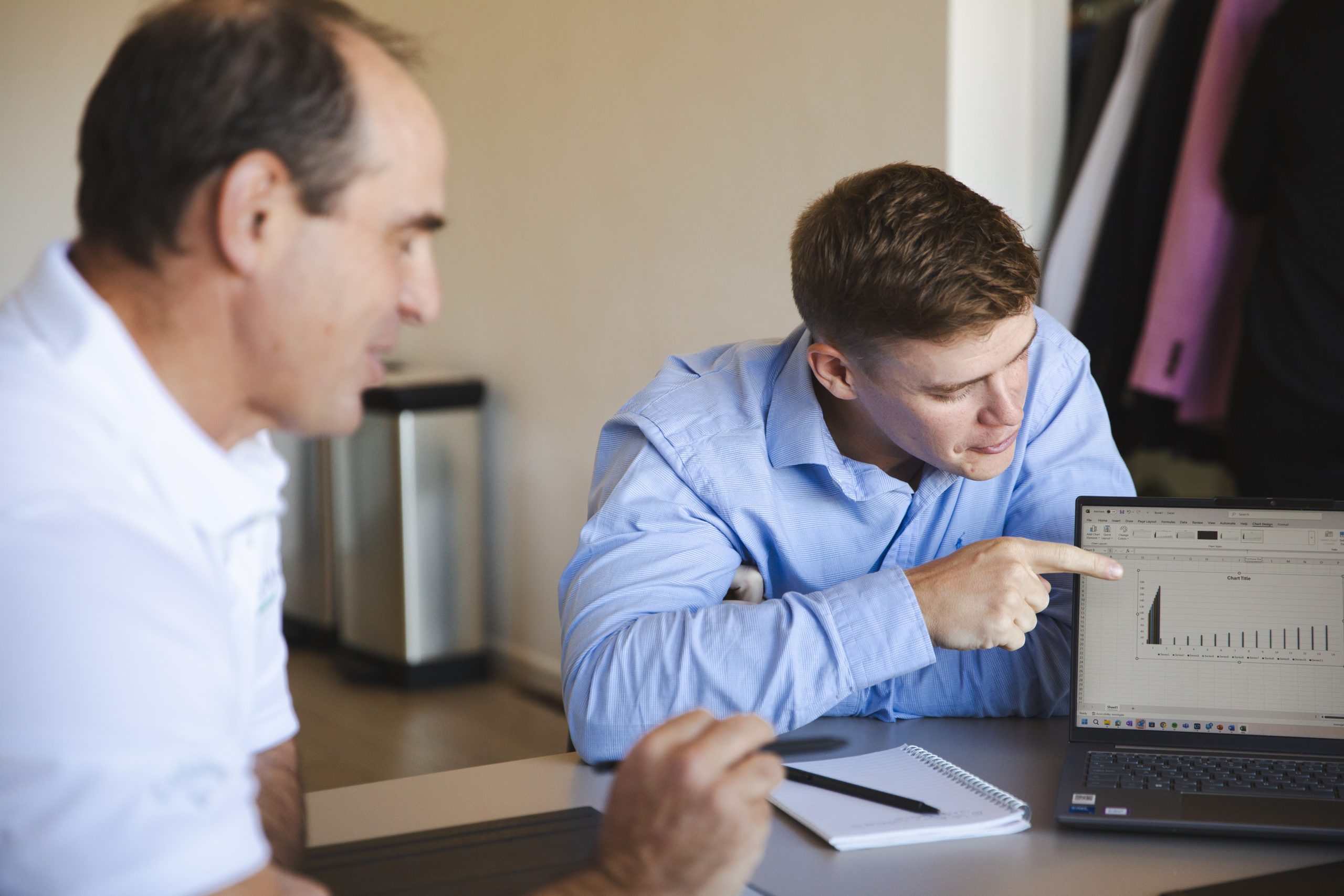 Craig and George circling round a laptop working with a client on Business Transformation Consulting